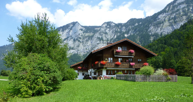Das Stockerhäusl im Sommer vor dem Untersberg, umgeben von grünen Wiesen